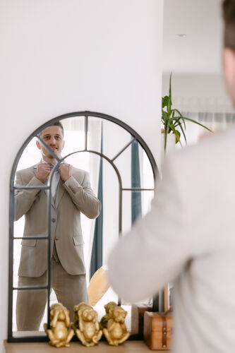 Marié ajustant sa tenue devant un miroir