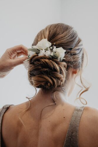 Coiffure de la mariée avec fleurs blanches pendant les préparatifs